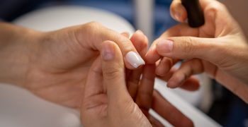 Nail care procedure in a beauty salon. Female hands and tools for manicure, process of performing manicure in beauty salon. Concept spa body care. Gloved hands of a skilled manicurist cutting cuticles