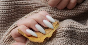 Beautiful hands of a young woman with white manicure on nails. Autumn winter nail design concept of beauty treatment.
